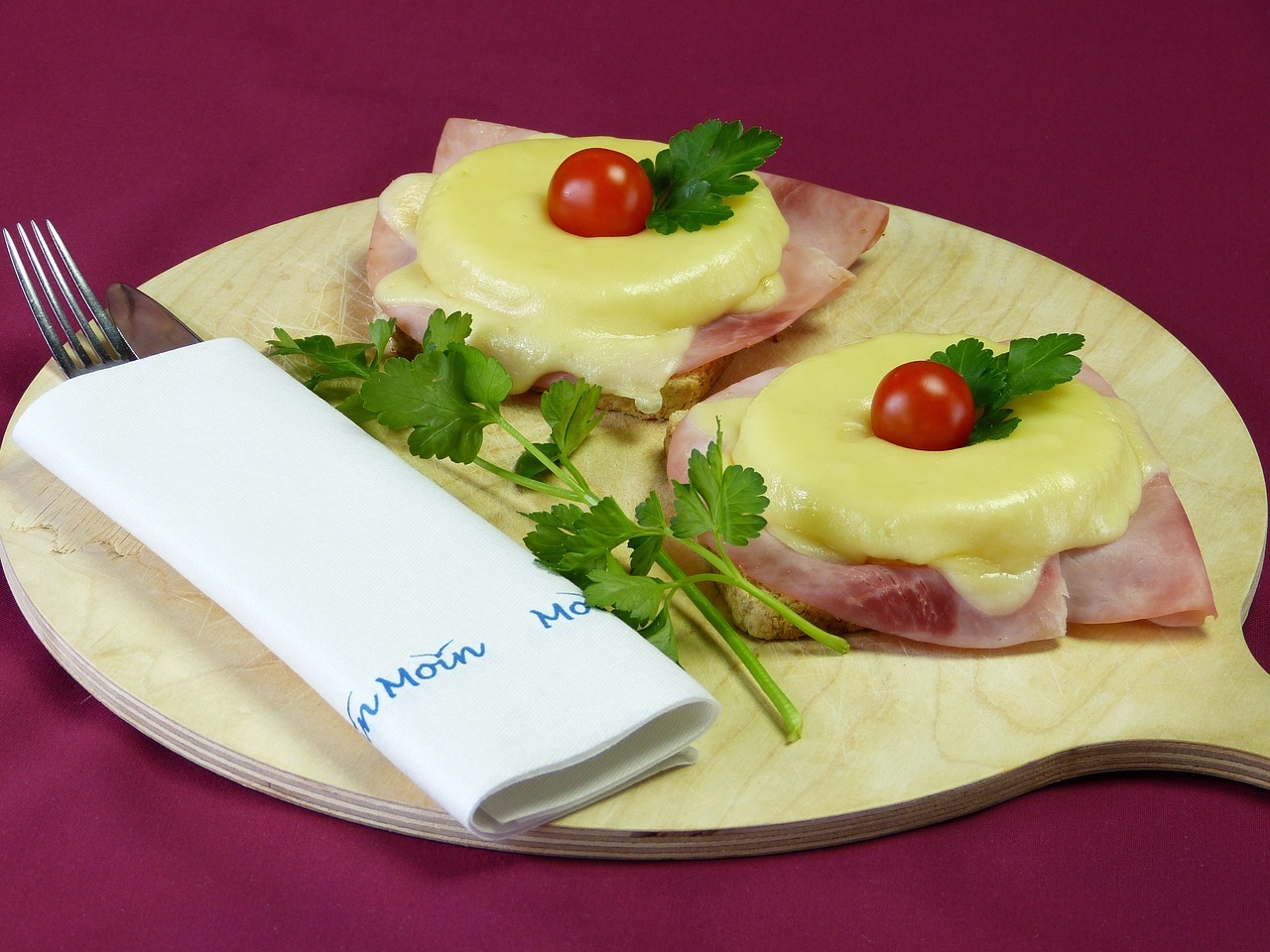 Käse-Schinken-Toast mit Ananas auf Holzbrett mit Kirschtomate und Petersilie, ideal für Feinschmecker und Snack-Liebhaber.