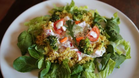 Gesunder Spinat-Salat mit frischem Gemüse, Brokkoli und Dressing auf einem Teller, ideal für eine ausgewogene Ernährung.
