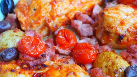 Gericht mit Hähnchenbrust, Kirschtomaten, Oliven und Speck, serviert in einer Pfanne, ideal für herzhafte Mahlzeiten.