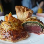 Gourmet Beef Wellinton mit Teigkruste, gefüllt mit Rindfleisch und Gemüse, serviert auf einem weißen Teller.