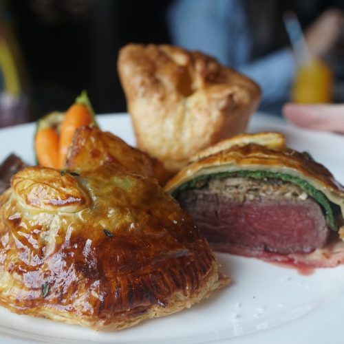 Gourmet Beef Wellinton mit Teigkruste, gefüllt mit Rindfleisch und Gemüse, serviert auf einem weißen Teller.