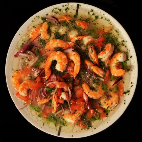 Frischer Garnelen-Ceviche mit Zwiebeln, Koriander und Limettensaft auf einem weißen Teller, ideal für Meeresfrüchte-Liebhaber.