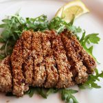 Sesamgebratener Thunfisch auf einem Bett aus frischem Rucola mit Zitronenscheibe, ideal für Feinschmecker und Liebhaber der asiatischen Küche.