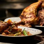 Gegrillte Hähnchenkeulen auf einem Teller mit Gemüse und Sauce, ideal für kulinarische Präsentationen und Rezepte.