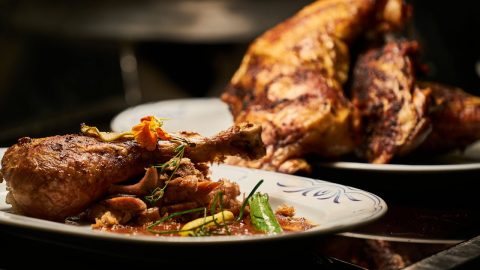 Gegrillte Hähnchenkeulen auf einem Teller mit Gemüse und Sauce, ideal für kulinarische Präsentationen und Rezepte.