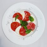 Frischer Caprese-Salat mit Mozzarella, Tomaten und Basilikum auf einem weißen Teller, ideal für gesunde Ernährung.