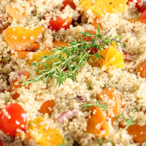 Quinoa-Salat mit frischen Tomaten, Orangenstücken und Thymian, gesund und nahrhaft, ideal für eine ausgewogene Ernährung.