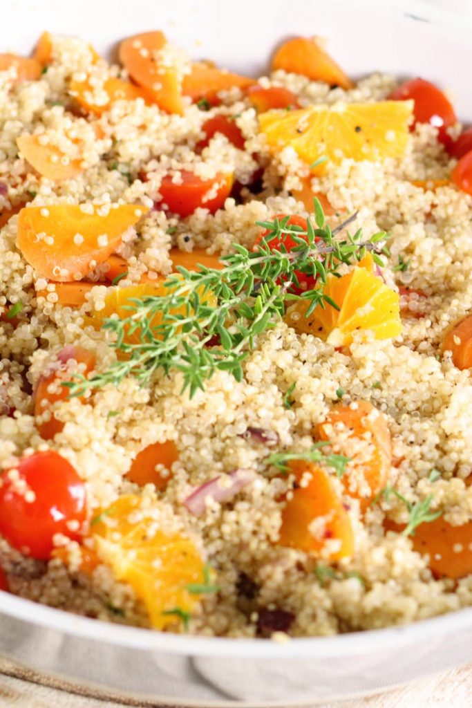 Quinoa-Salat mit frischen Tomaten, Orangenstücken und Thymian, gesund und nahrhaft, ideal für eine ausgewogene Ernährung.