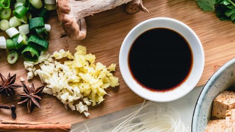 Frische Zutaten für asiatische Nudelsuppe: Pilze, Frühlingszwiebeln, Koriander, Ingwer, Knoblauch, Sojasauce und Reisnudeln.