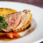 Ente a l'orange, perfekt gegart, serviert mit Gemüse und einer köstlichen Sauce auf einem weißen Teller.