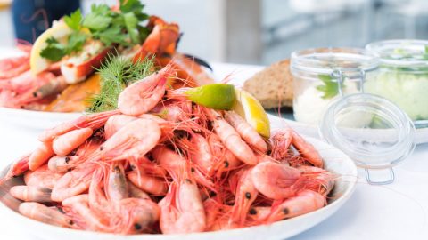 Frische Garnelen auf einer Meeresfrüchte-Platte, serviert mit Zitrone und Kräutern. Ideal für Feinschmecker und Seafood-Liebhaber.