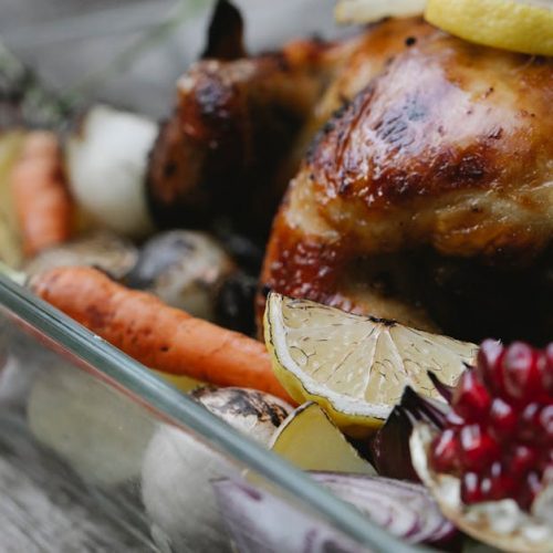Geröstetes Hähnchen mit Zitrone und buntem Gemüse in einer Auflaufform, ideal für festliche Anlässe und Familienessen.