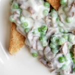 Erbsen und Lachs in cremiger Sauce auf geröstetem Brot, ein herzhaftes Gericht mit frischen Zutaten und cremiger Textur.