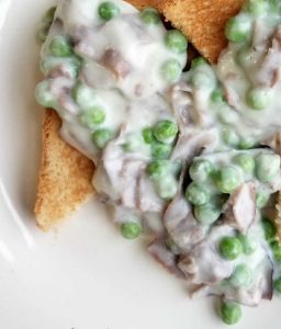 Erbsen und Lachs in cremiger Sauce auf geröstetem Brot, ein herzhaftes Gericht mit frischen Zutaten und cremiger Textur.