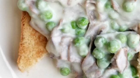 Erbsen und Lachs in cremiger Sauce auf geröstetem Brot, ein herzhaftes Gericht mit frischen Zutaten und cremiger Textur.