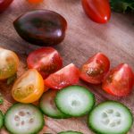 Frisches Gemüse mit Gurken, Tomaten und Salat auf einem Holzbrett, ideal für gesunde Rezepte und Ernährung.