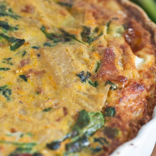 Leckere Gemüse-Quiche mit Spinat, Käse und einer goldbraunen Kruste, ideal für ein herzhaftes Gericht.