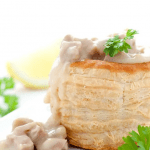 Blätterteig-Törtchen gefüllt mit Hähnchen und einer cremigen Sauce, garniert mit frischen Kräutern und Zitrone.