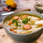 Eine Schüssel mit Erbseneintopf, gefüllt mit Karotten, Brokkoli und weiteren Gemüsesorten, serviert in einer modernen Schüssel.