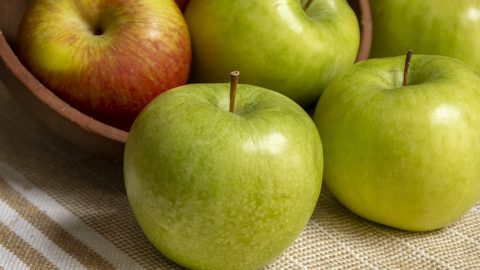 Eine Schüssel mit roten und grünen Äpfeln, die auf einem Tisch liegen. Frische Äpfel für gesunde Snacks oder Rezepte.