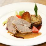 Ein Teller mit zartem Kalbsschnitzel, gebratenen Kartoffeln, Gemüse und einer Sherry-Sauce, serviert auf einem weißen Teller.