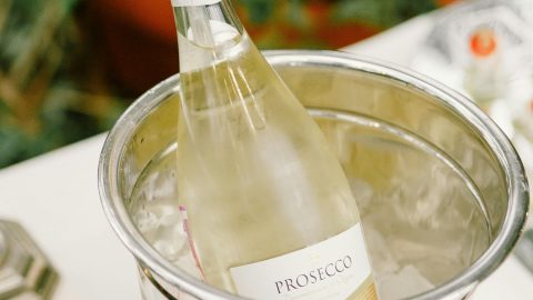 Eine Flasche Prosecco steht in einem silbernen Eiskübel, umgeben von Eis. Ideal für festliche Anlässe und Feiern.