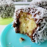 Ein Stück Kokos-Schokoladenkuchen mit einer Bissstelle, umhüllt von Kokosraspeln und Schokoladenglasur.