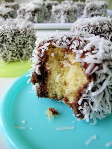 Ein Stück Kokos-Schokoladenkuchen mit einer Bissstelle, umhüllt von Kokosraspeln und Schokoladenglasur.